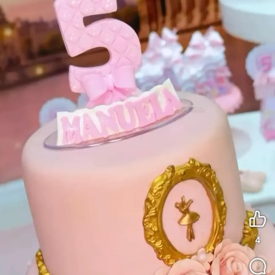 Detalhe do topo de bailarina e das flores de um bolo decorativo rosa